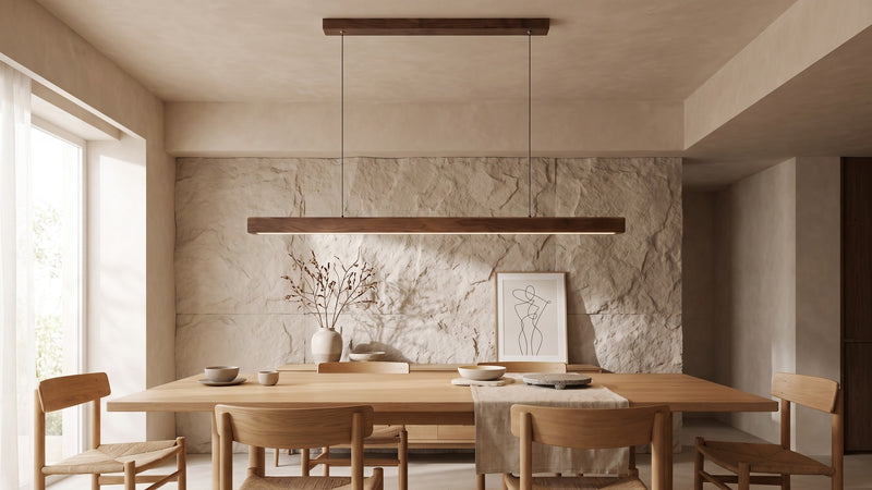 Suspension linéaire en bois accrochée au-dessus d'une table à manger en bois, devant un mur en pierre claire