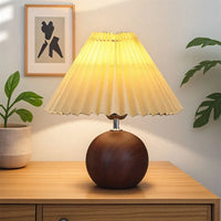 Lampe à poser plissée pied métal noir, vue trois quarts sur bureau bois