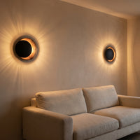 Applique Aurore coloris cuivre noir, avec un jeu de lumière au mur, allumée