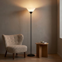 Lampadaire Flambeau coloris noir, avec un jeu de lumière au mur, allumée