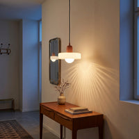 Suspension Auréole coloris rose - blanc, avec un jeu de lumière au mur, allumée